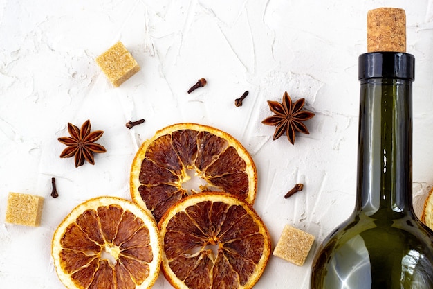 Bottle of wine and spice on white background. Ingredients for a mulled wine. Cinnamon, anise stars, orange, brown sugar, cloves. Christmas hot drink