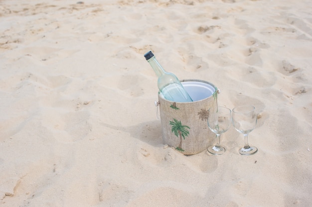 Bottle of wine and two glasses on sandy beach