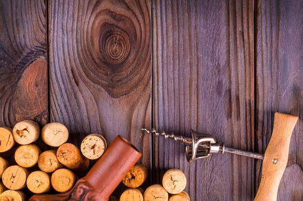 La bottiglia di vino con tappi di sughero sul fondo della tavola in legno.