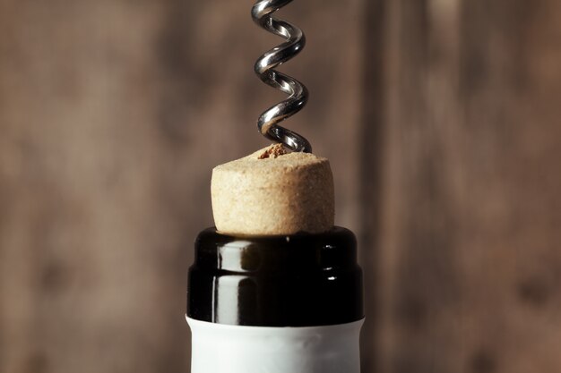 Bottle of wine with corkscrew on wood