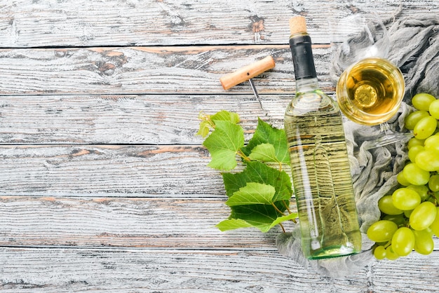 A bottle of wine with glasses and grapes Leaves of grapes Top view On a white wooden background Free space for text