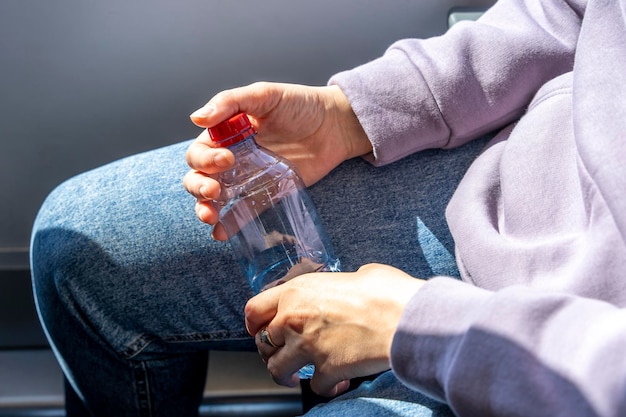 Foto bottiglia con acqua potabile pulita nella mano di una ragazza