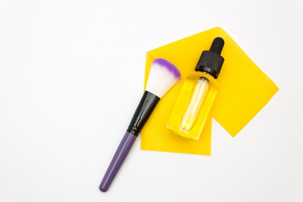 Bottle with dropper on white and a large brush for makeup or blush