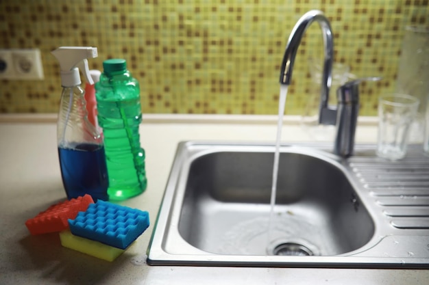 Бутылка с экологически чистым моющим средством для мытья посуды на фоне домохозяйки, моющей посуду