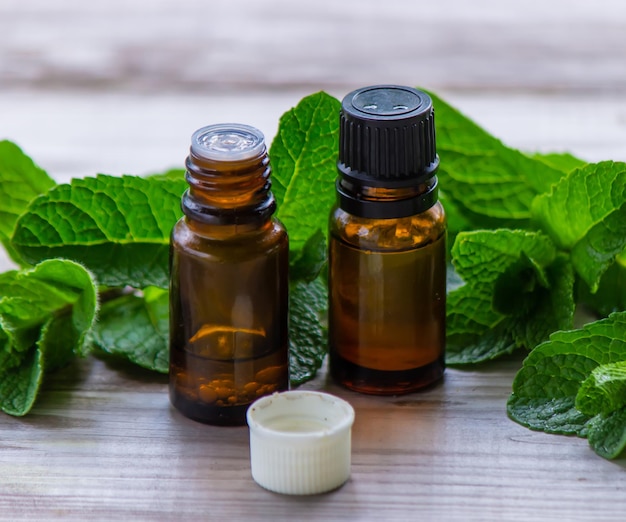 Bottle with essential oil and mint isolated on a light background