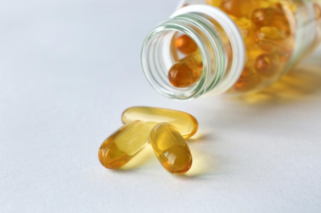 Bottle with fish oil capsules on white background