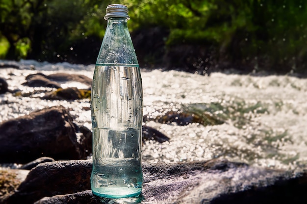 Bottiglia con acqua fresca fresca su una roccia