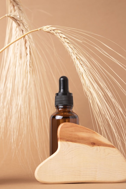 ベージュの背景に木製のグアシャとローション セラム エッセンシャル オイルのボトル ナチュラル オーガニック エコ化粧品 小麦と大麦から作られた自然化粧品