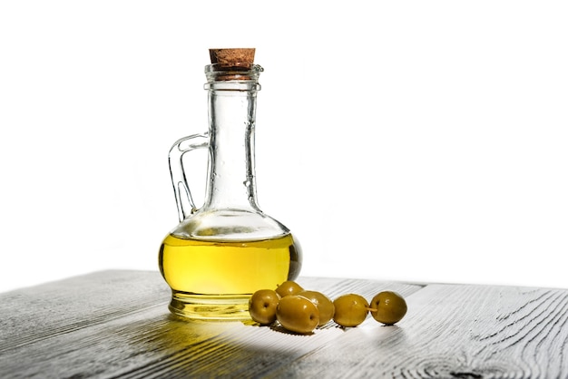 Bottle with olive oil and a few olives on a white wall with copy space.