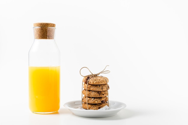 Bottle with orange juice and cookies on white background