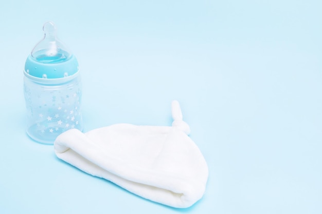 Bottle with a pacifier and a cap for a baby on a blue background with copy space