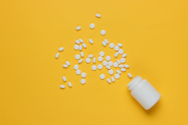 Bottle with pills on yellow background