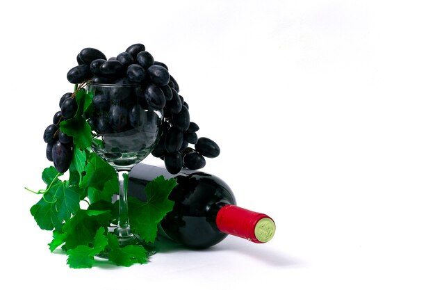 Bottle with red wine, wine glass with grapes