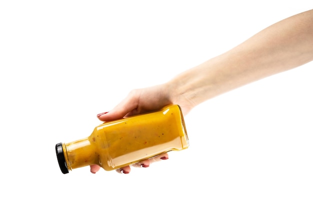 Бутылка с соусом в женской руке на белом фоне