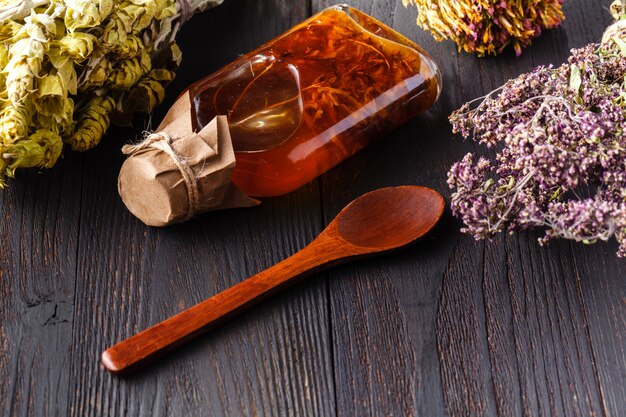 Bottle with vegetable oil with herbs on wood rustic table