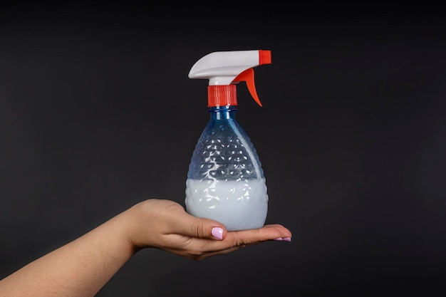 水スプレーを入れたボトルが家用の家具の手のひらに置かれています