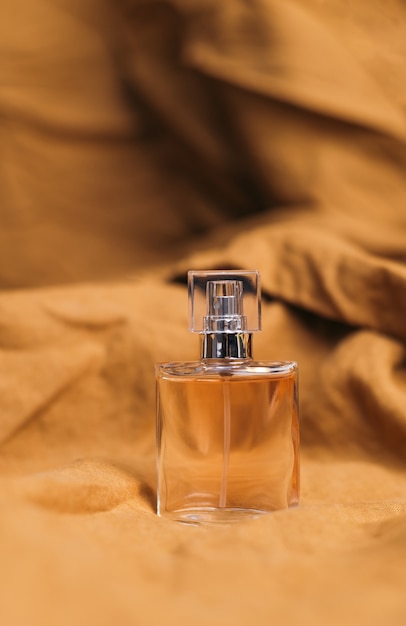 A bottle of women's fragrant perfume on a brown textured fabric