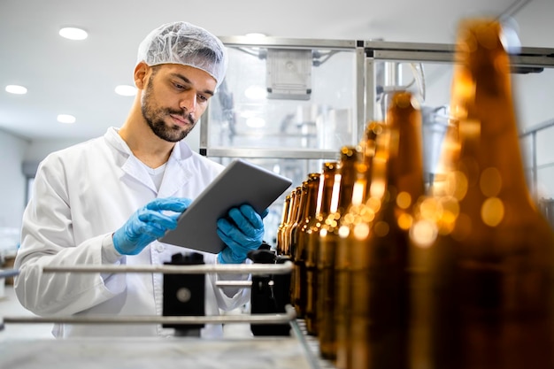 Bottled beer beverage production and factory worker controlling process on tablet computer