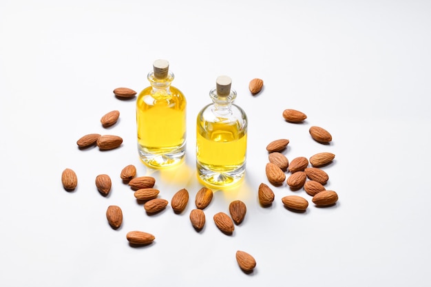 Bottles of almond oil and almonds on white background copyspace