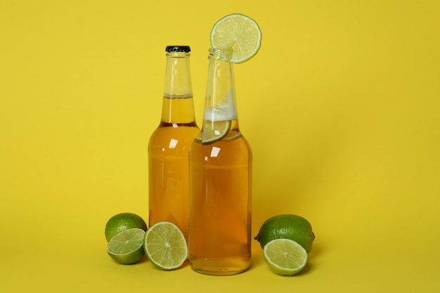 Bottles of beer and limes on yellow