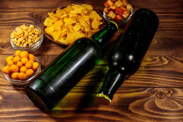 Bottles of beer and various snacks for beer on wooden table