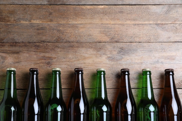 Bottles of beer on wooden table flat lay Space for text