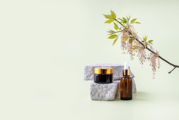 Bottles for cosmetics on the podium made of stone and branches of flowering ash maple