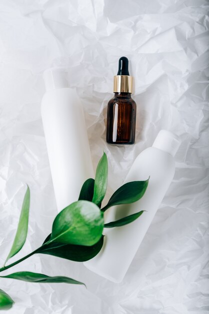 Bottles of cosmetics on white crumpled paper