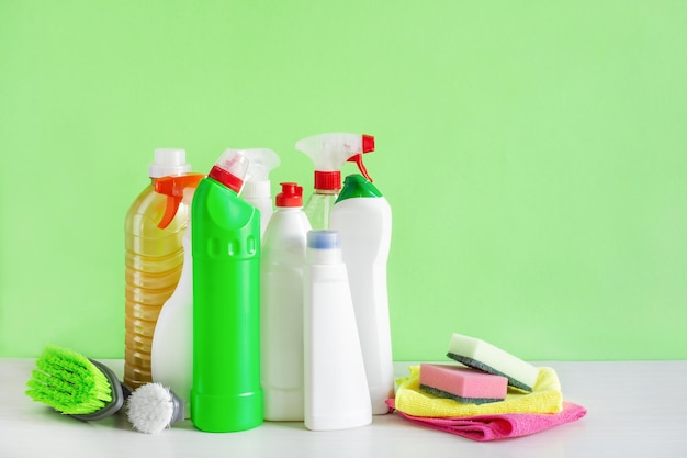 Bottles of detergent and cleaning tools over green background