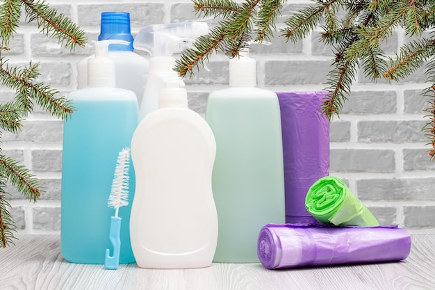 Bottles of detergent and garbage bags on gray background