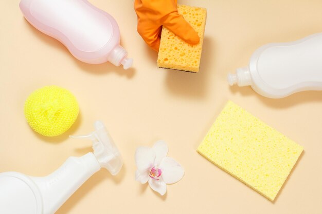 Bottles of dishwashing liquid and sponges on a beige background