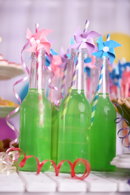 Bottles of drink with straw on decorative background