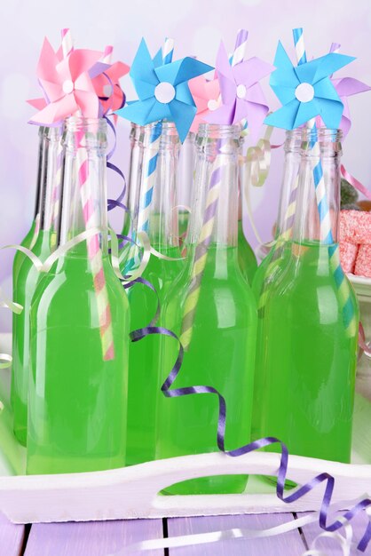 Photo bottles of drink with straw on table on bright background