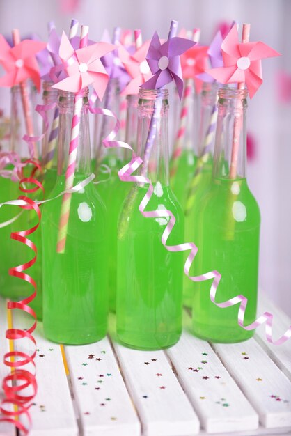 Bottles of drink with straw on table on decorative background