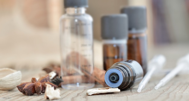 Bottles of essential oil and spices on a wooden table with pipette to extract essence