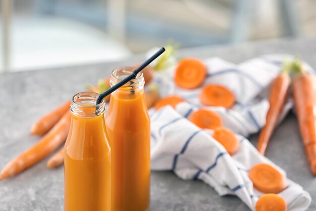 Bottles of fresh carrot juice on grey table