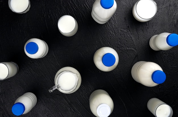 bottles and glasses with milk on black background