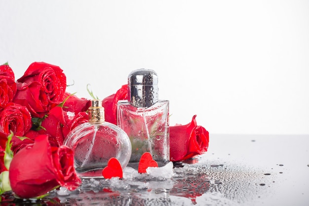 Bottles of male and female perfume, red roses, decorative hearts.