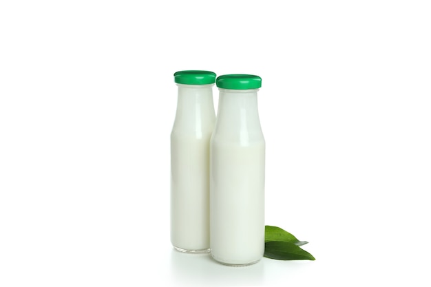 Bottles of milk and leaves isolated on white