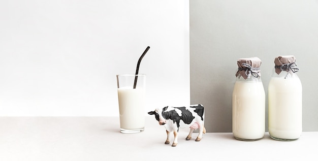 Фото Бутылки свежего молока фигурка коровы и стакан молока