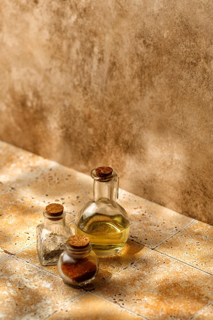 Bottles of oil and spices on beige background tile in sunny light Sunshine Eastern concept