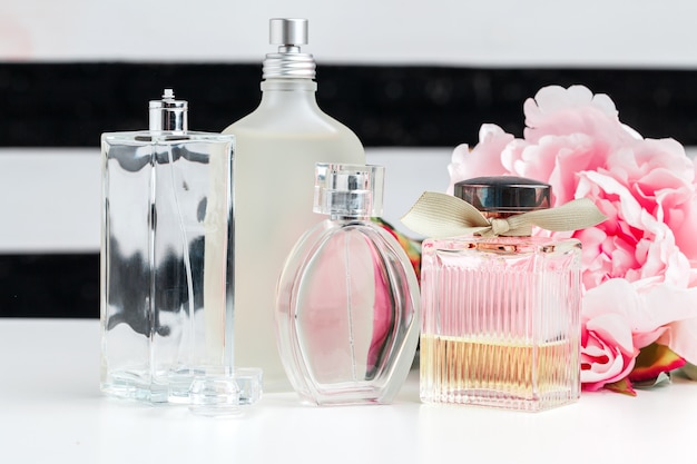 Bottles of perfume with flowers on white 