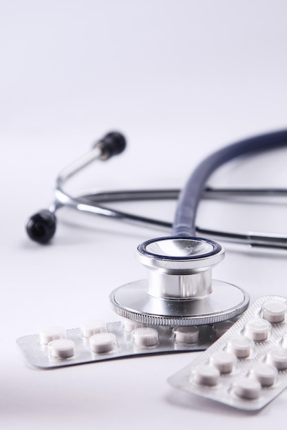 Bottiglie di pillole e uno stetoscopio medico su sfondo bianco