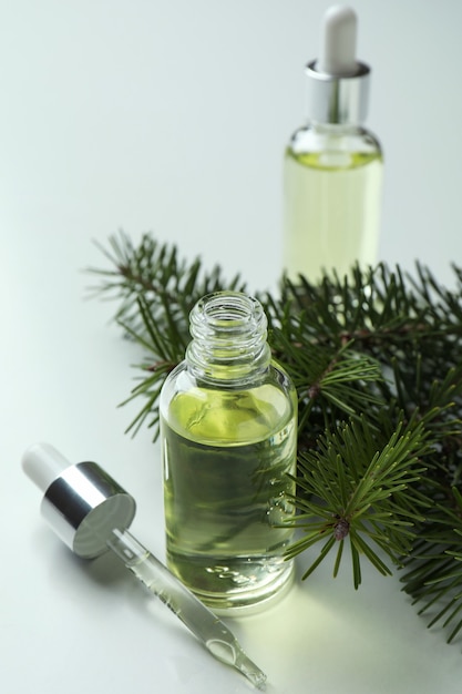 Bottles of pine oil and twig on white