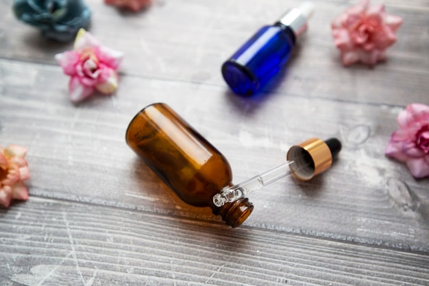 bottles and a pipette with hyaluronic serum for cosmetic and cosmetic procedures on a wooden background with flowers