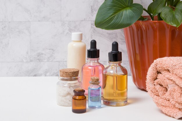 Bottles of tincture, salt, oil or serum, a towel and a plant in the bathroom