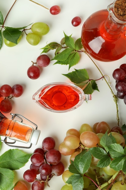 Bottles of vinegar and grape on white background, top view