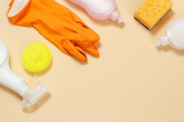 Bottles of washing liquid rubber gloves and sponges on a beige background