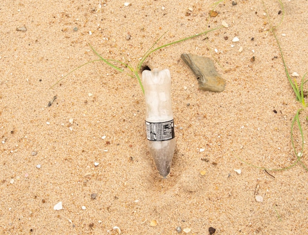 Bottles of water (embroidered into the sand) discarded on the beach and sand.