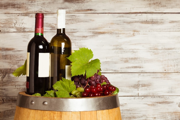 Bottles of wine on the oak barrel over old shabby wooden background